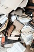Ein Haufen alter Dokumente, Ordner, Bücher und Zeitungen.