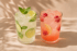 Zwei Gläser Limonade: eine mit Limette und Minze, die andere mit Himbeeren.