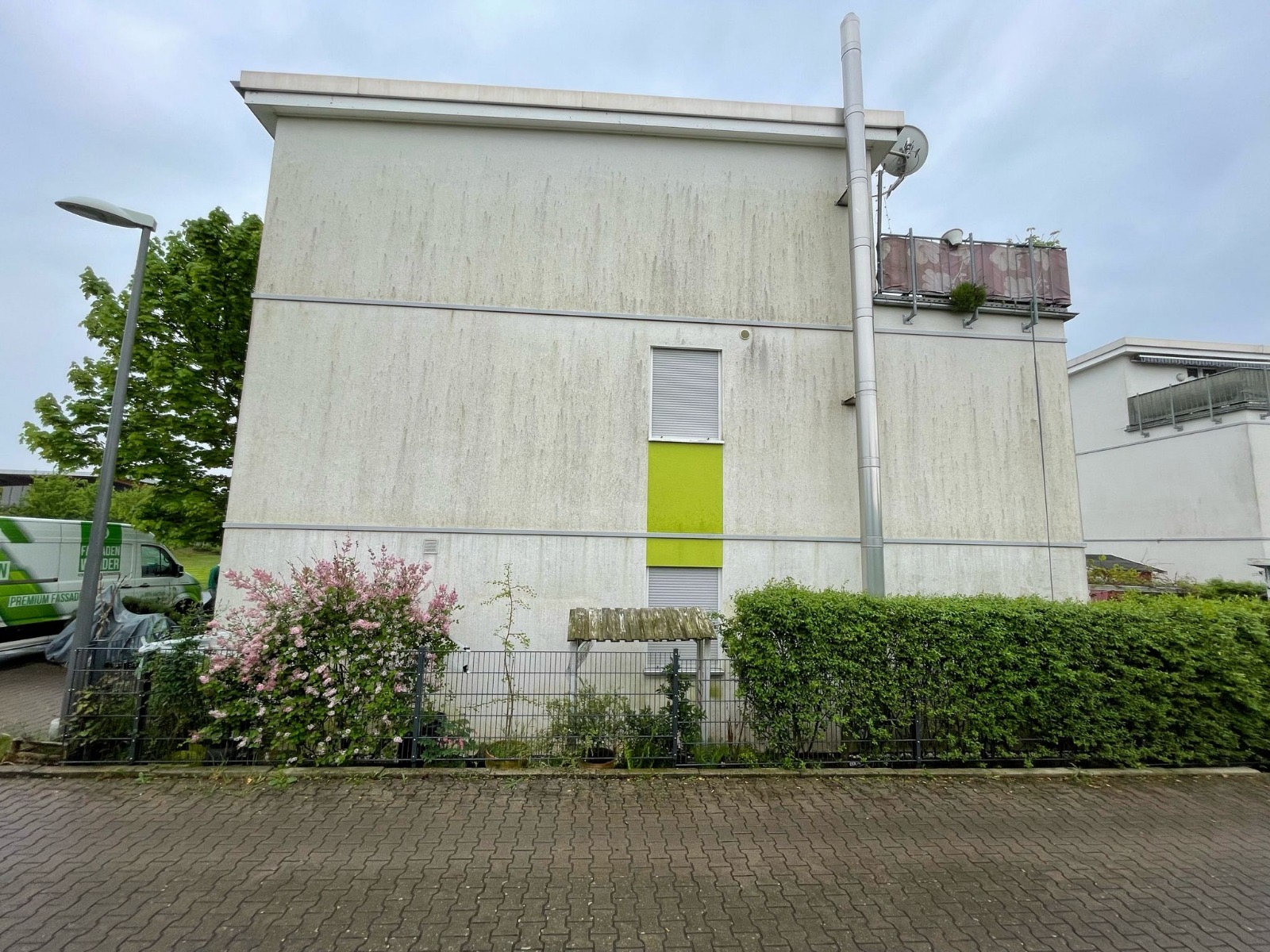 Gewerbegebäude vor der Reinigung mit deutlichem Algenschleier auf der Fassade