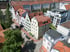 Hinterhof mit weißem Gebäude, 5 Mülltonnen und einem geparkten weißen Lieferwagen auf dem Pflaster.