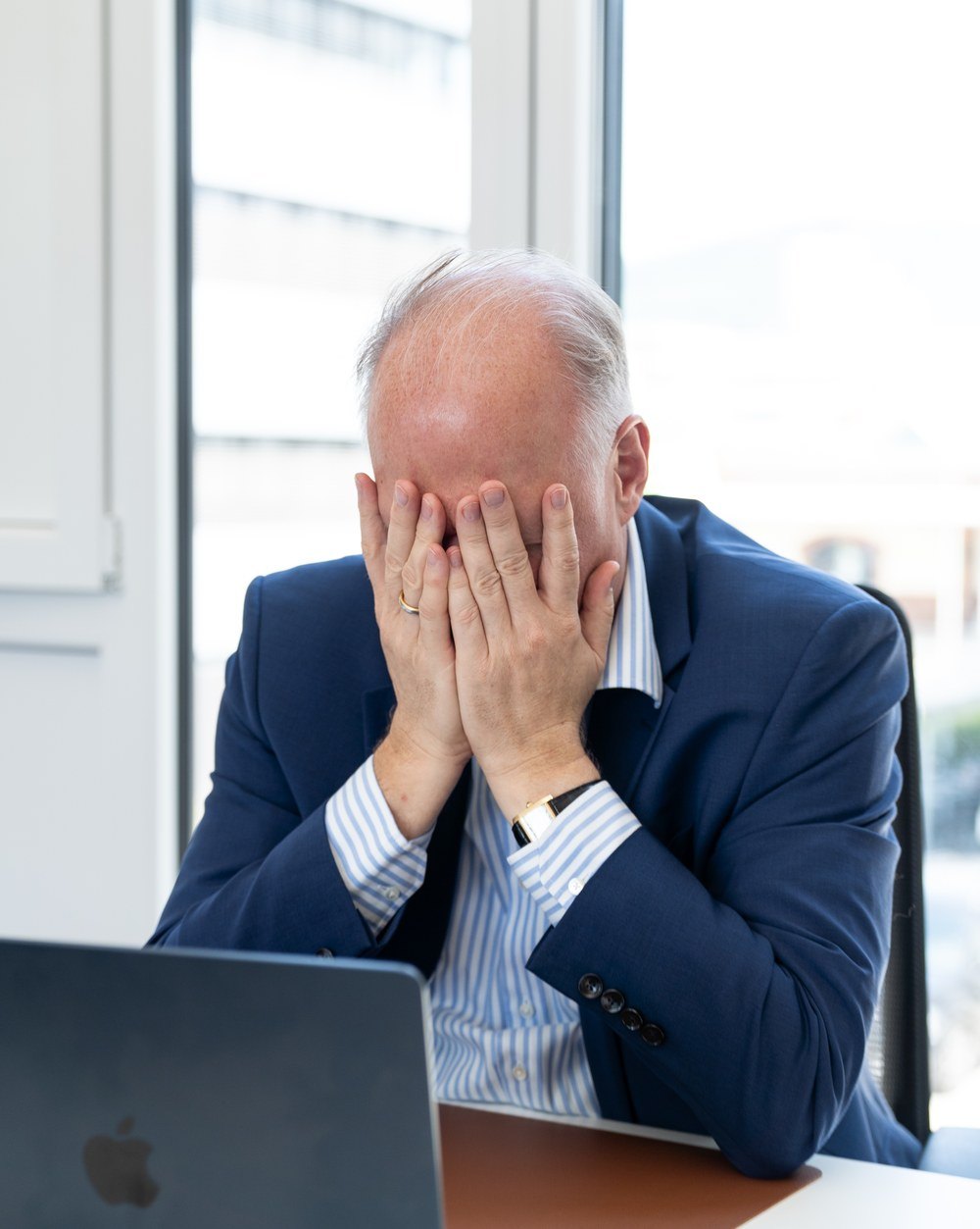 Führungskraft am Schreibtisch, Hände vor dem Gesicht
