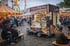 Foodtruck "Crepes & Poffertjes" auf einem Kirmesplatz mit Karussells und Riesenrad bei Dämmerung.