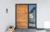 Moderne Haustür aus Holz und Glas mit silbernem Griff und Klingel an weißer Wand.