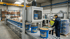 Ein Arbeiter füllt Eimer mit Mörtel an einer Vakuum-Kammer-Maschine in einer Fabrikhalle.
