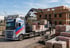 Volvo LKW mit Ladekran entlädt Paletten mit Baumaterial vor einem im Bau befindlichen Backsteingebäude.