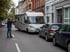 Mann weist einem weißen Wohnmobil auf einer engen Straße zwischen parkenden Autos den Weg.