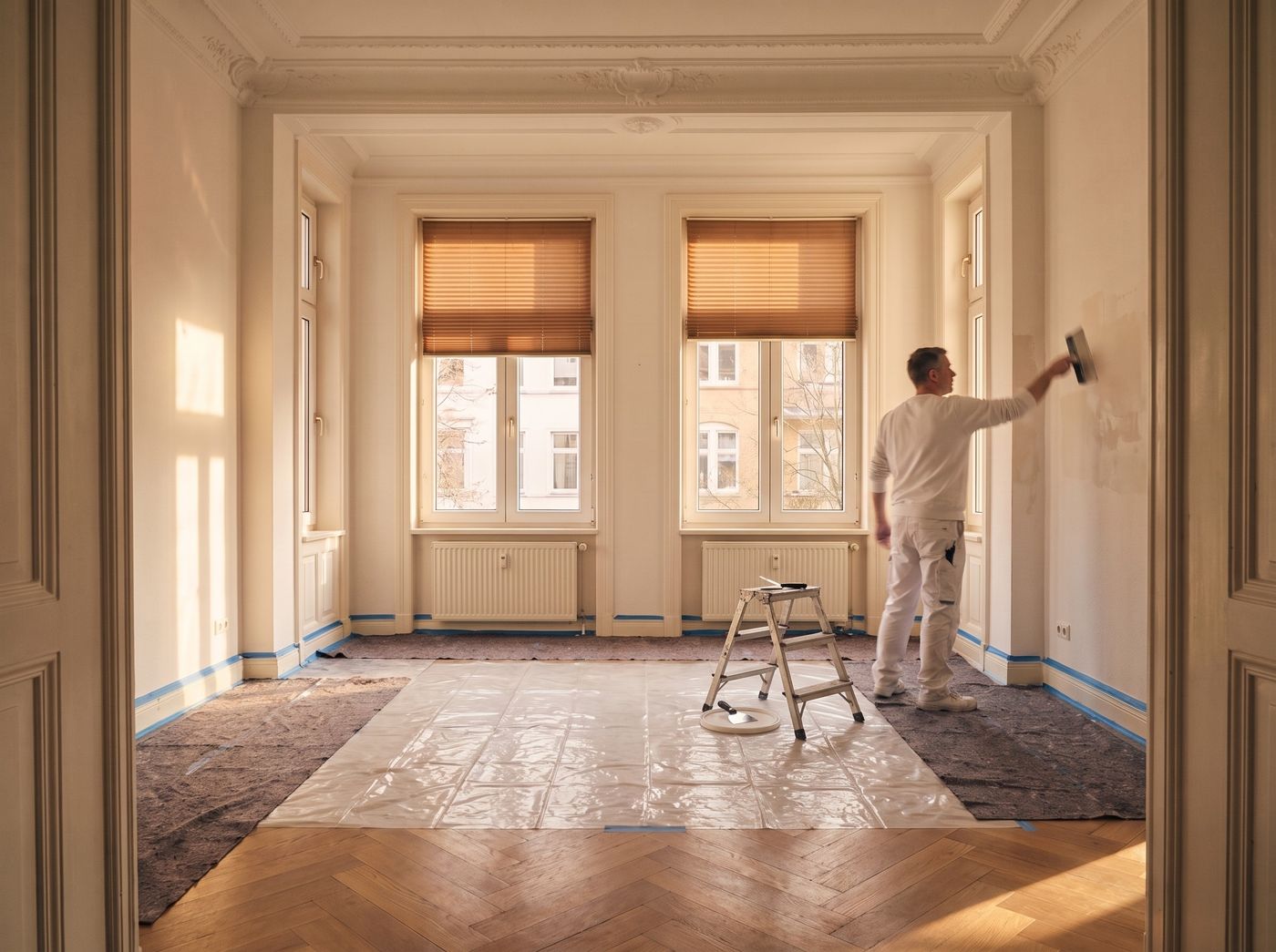 Maler spachtelt die Wand im selben Raum