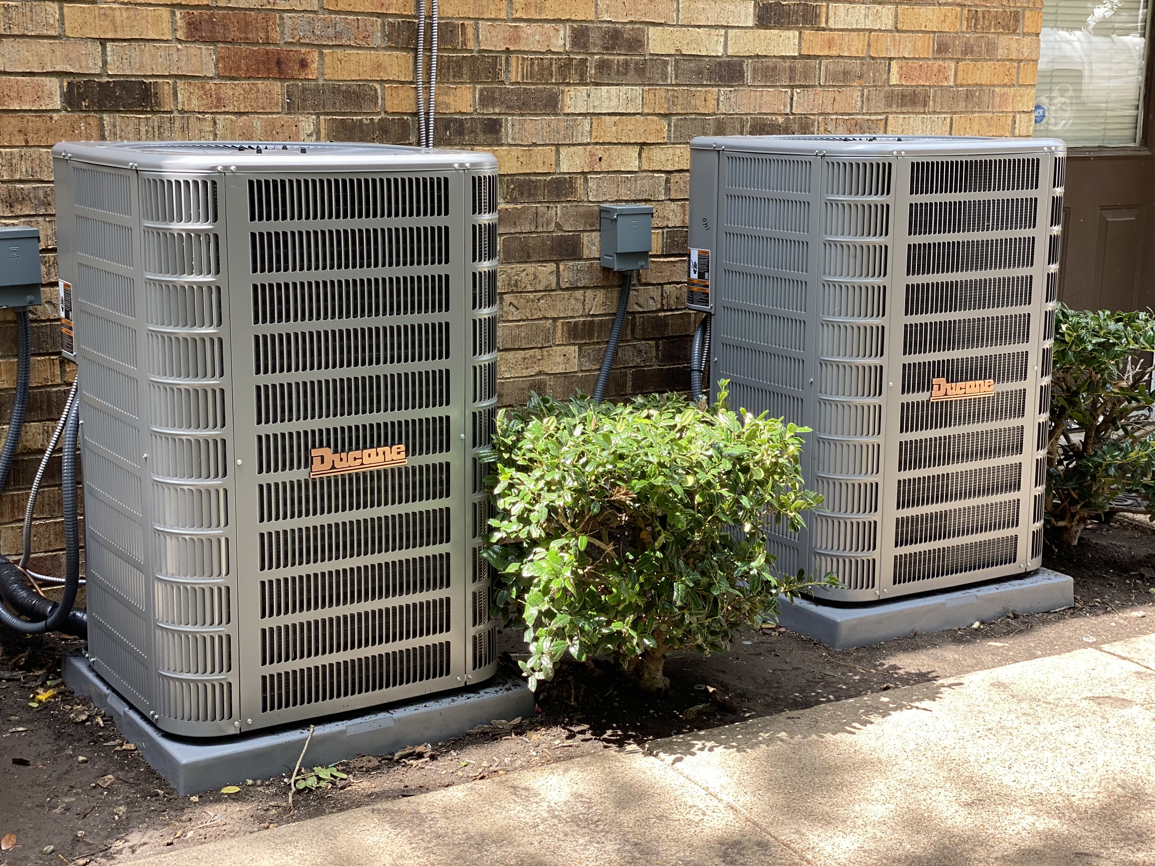 Two Ducane outdoor condensers installed side by side on concrete pads