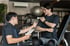 Zwei Männer unterhalten sich in einem Fitnessstudio über Schulterübungen nach einer Operation