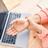 Person experiencing wrist pain from arthritis at desk with laptop