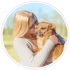 Blonde Frau küsst einen braunen Hund auf den Kopf.