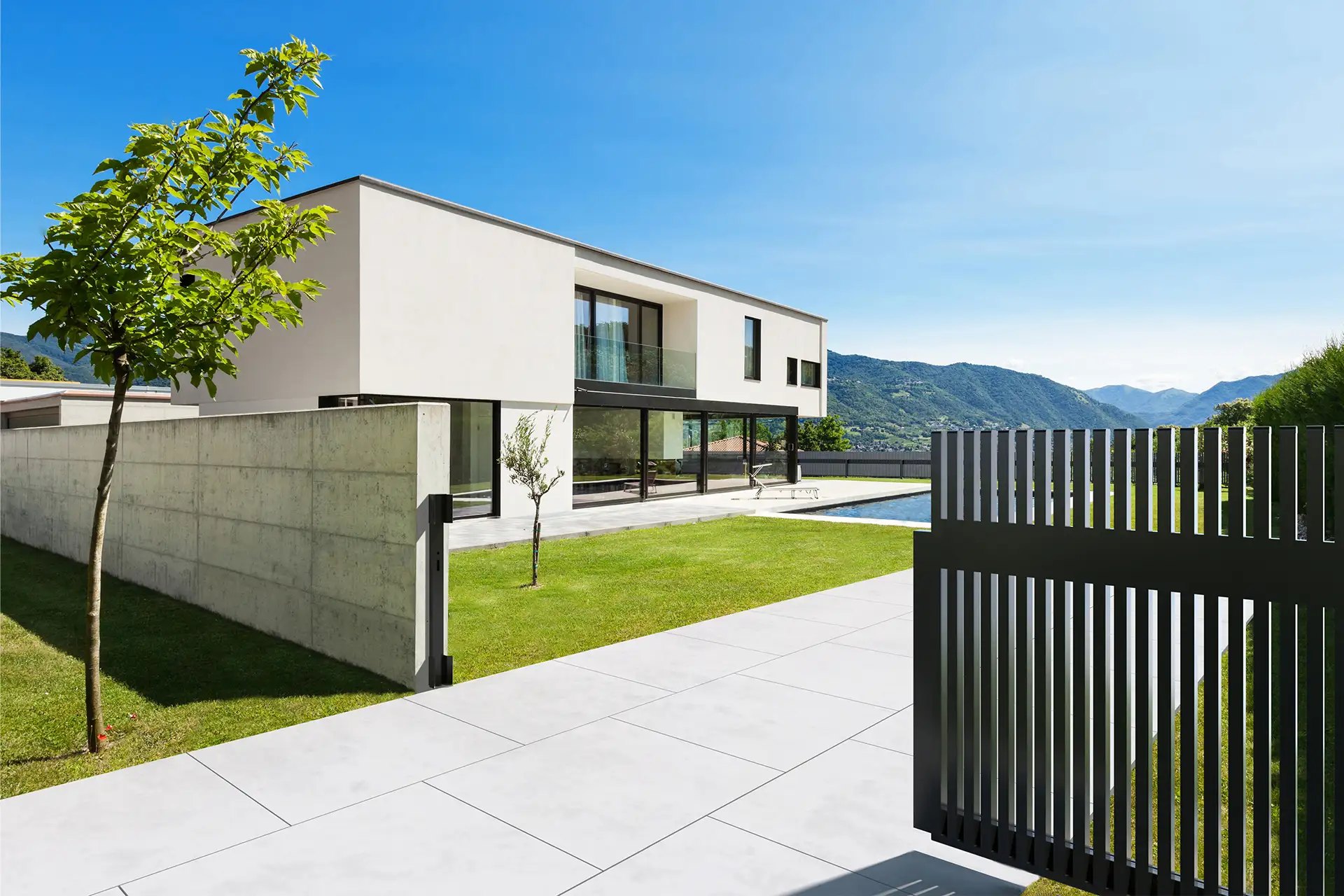 Modernes Haus mit Pool und Bergblick hinter einem GUARDI Aluzaun mit senkrechten Latten