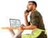 Ein Mann mit Brille und grüner Schürze telefoniert am Laptop mit Diagrammen an einem Holztisch vor schwarzem Hintergrund.