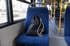 Schwarzer Turnbeutel mit weißen Kordeln auf einem leeren blauen Bussitz, Fenster und Innenraum sichtbar.