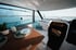 Moderner Innenraum einer Yacht mit Sitzecke, Holztisch, Panoramafenstern und Blick auf das Meer unter einem Dachfenster.
