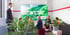 Personen sitzen in einem Raum mit Pflanzen, während eine große Leinwand "TECHEM – MAKING BUILDINGS GREEN, SMART AND HEALTHY" zeigt.