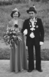 Eine Frau im Kleid mit Krone und ein Mann in Tracht mit Hut, Medaillen und Blumenstrauß.