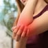 Woman holding her sore elbow as she experiences joint pain.