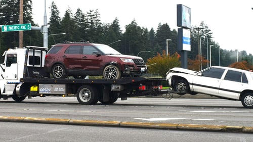 Car secured on a flatbed tow truck deck, the flatbed vs wheel-lift towing choice for drivers in Normal, IL