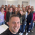 Ein Mann macht ein Selfie mit einer Gruppe von 22 lächelnden Frauen.