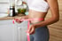 Woman measures waist as part of semaglutide weight loss program.