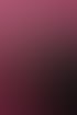 Ein lächelndes Paar in schwarzer Kleidung umarmt sich eng vor einem pinkfarbenen Hintergrund.
