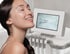Lächelnde Frau mit strahlender Haut neben einem kosmetischen Behandlungsgerät mit dem Display-Text „Get your glow!“.