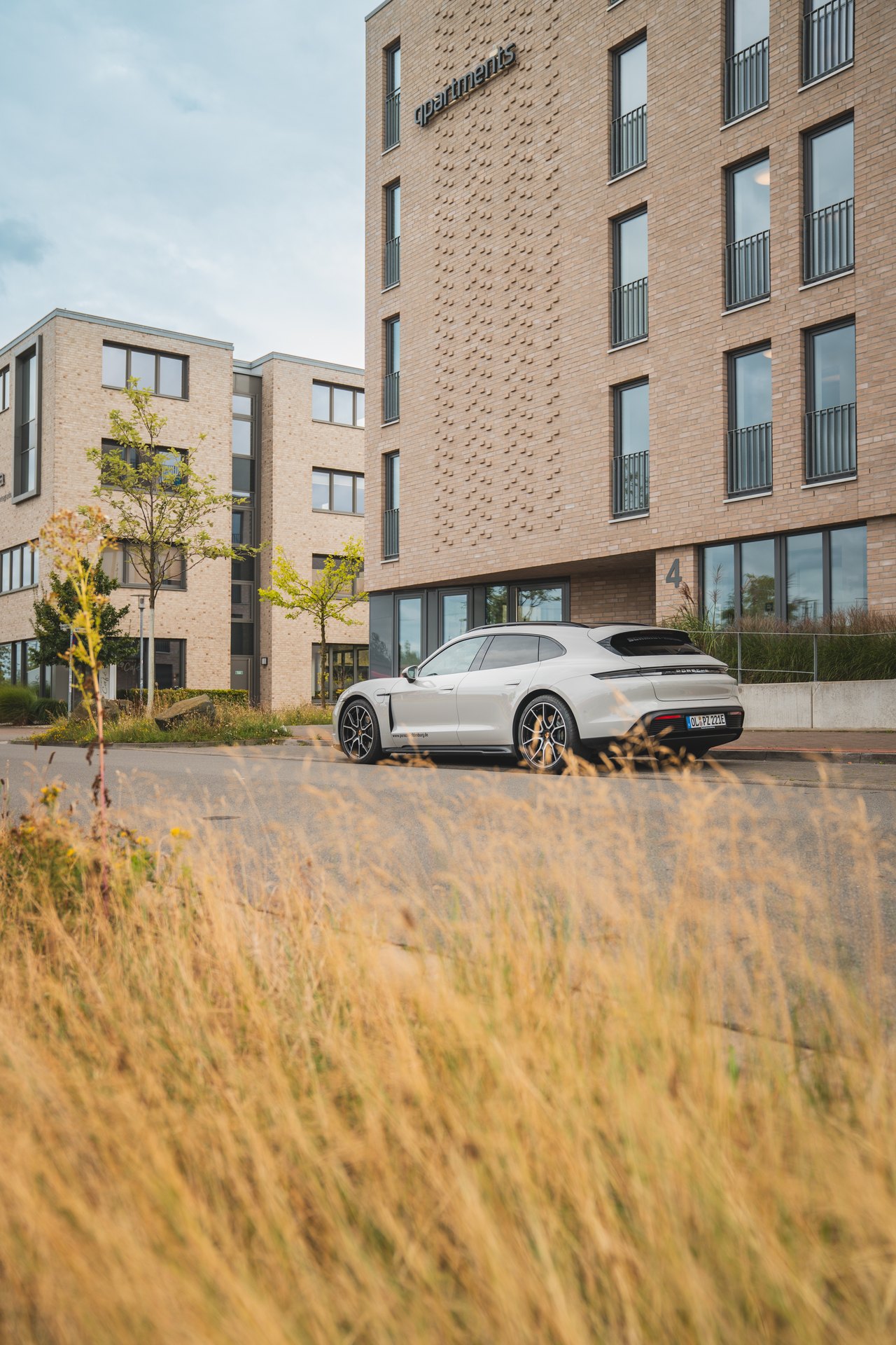 Weißer Porsche Taycan vor modernem Gebäude