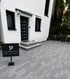 Modern gepflasterte Hauseinfahrt mit grauen Rechtecksteinen, Treppe und Werbeschild der Pflastermanufaktur.