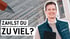 Drei Personen, zwei Männer in Anzügen und eine Frau im weißen Hosenanzug, stehen lächelnd in einem modernen Büroflur.