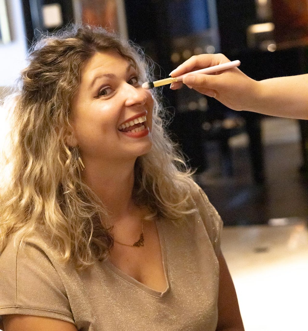 Eine Frau lacht beim Make-up vor einem Business-Fotoshooting
