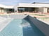 Ein moderner Naturpool mit hellblauem Wasser im Außenbecken vor einem weißen Gebäude mit Glasfront.