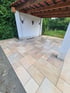 Überdachte Terrasse mit hellen Natursteinplatten in verschiedenen Formaten und einer weißen Wand mit Hirschgeweihen.