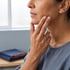 A person touches their jawline with two fingers.