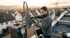 Techniker installiert eine Satellitenschüssel auf einem Hausdach und nutzt ein digitales Messgerät zur Signalausrichtung.