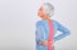 Older woman clutches lower back, highlighting sciatica pain area.