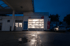 Tankstelle in der Dämmerung mit beleuchteter Garage, in der sich ein Auto befindet.