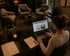 Frau arbeitet am Laptop am Schreibtisch in einem modern eingerichteten Büro mit Sitzgruppe im Hintergrund.