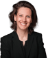 Eine Frau mit braunem, schulterlangem Haar und einem schwarzen Blazer lächelt.
