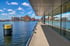 Moderner Kai mit Glasgebäude und Binnenhafen unter blauem Himmel.