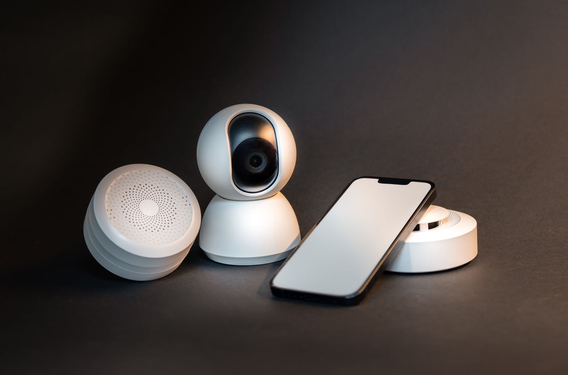 Home security app on a phone beside smart home sensors