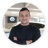 Mann mit verschränkten Armen lächelt in die Kamera, im Hintergrund ein Mazda-Logo und ein Auto.