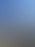 Ein Zimmermann steht auf einem hölzernen Dachstuhl im Rohbau unter blauem Himmel neben einem Baukran.