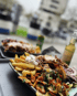 Ein Teller mit Dönerfleisch, Pommes, Süßkartoffelchips, Salat und Soße.