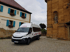 Weißer Iveco Daily Kastenwagen auf Kopfsteinpflaster vor Rathaus und Kirche.