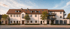 Modernes Wohnhaus mit braunem Ziegeldach, weißen Wänden, Fenstern, Balkonen und Garagen.