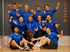 Eine Gruppe von 10 Personen und einem Hund in blauen T-Shirts posiert in einem Fitnessstudio mit „jukulojo Fitnesslab“-Logo.