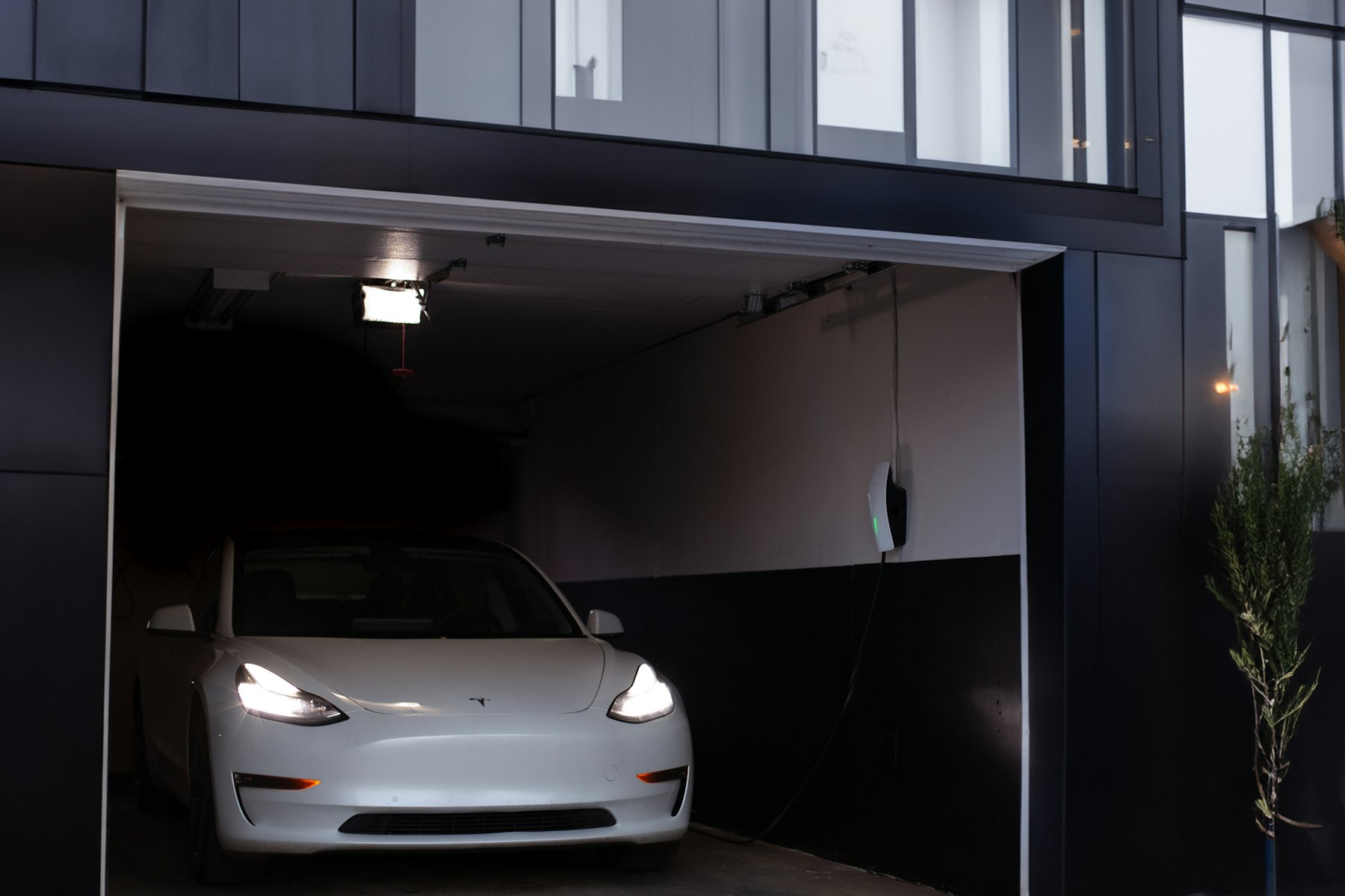 White electric car parked in a Yorba Linda garage beside a wall connector