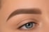 Nahaufnahme eines weiblichen Gesichts mit blauen Augen und perfekt geformter, brauner Augenbraue.