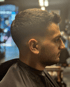 Ein Mann im Profil, der einen frischen Haarschnitt mit Fade-Übergang und Bart trägt.